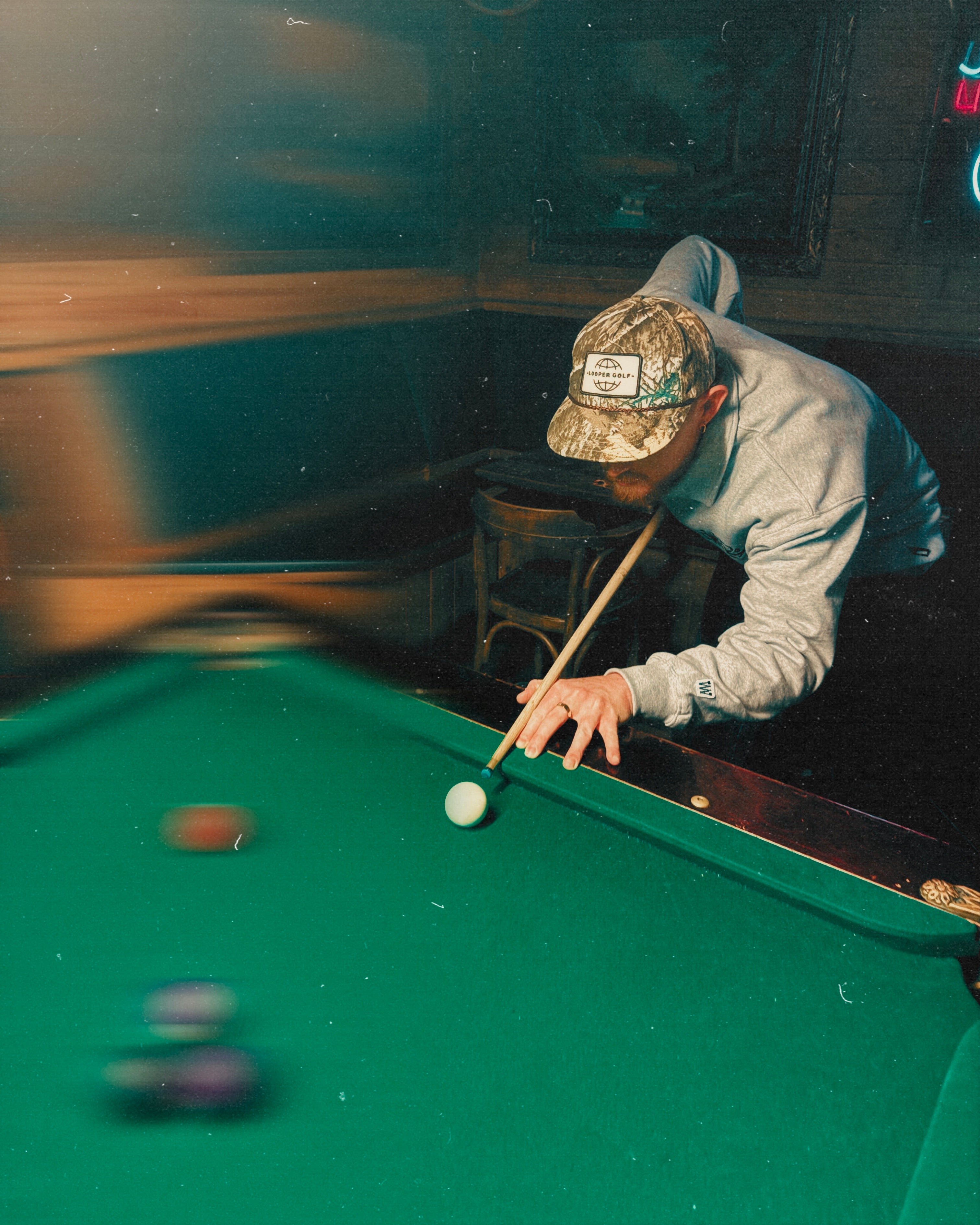Person playing pool in a dimly lit room