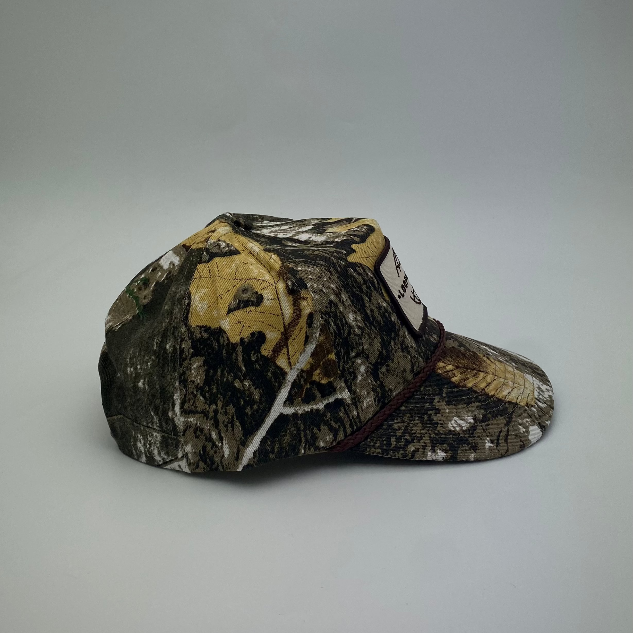 LOOPER Patch Cap V1 Bushland Camo lifestyle shot — unique camo pattern, snap strap, semi-curved brim
